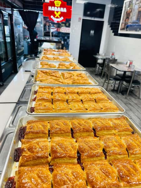 Several trays of neatly arranged guava pastries on a service line in a brightly lit bakery. The Havana Express logo is visible in the background.