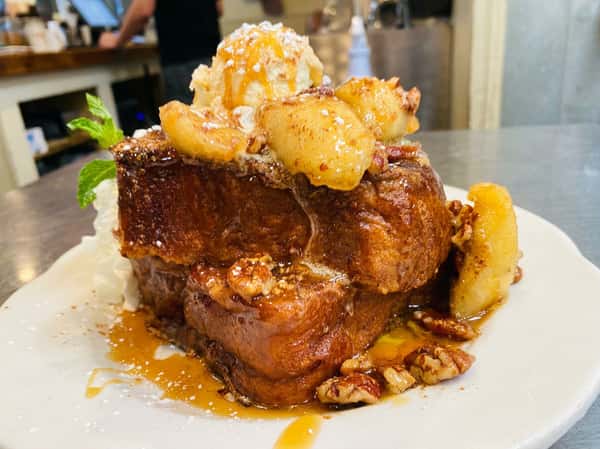 French toast slices topped with a scoop of ice cream, powdered sugar, cinnamon, and a mint leaf.