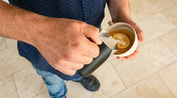 Barista pouring freshly brewed espresso into a white coffee cup at Cafe Remedy.
