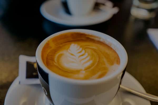Close-up of a freshly prepared latte with leaf-shaped foam art served in a ceramic cup at Cafe Remedy.