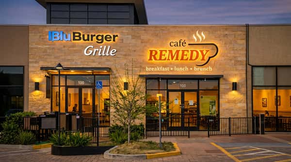 Cafe Remedy storefront next to Blu Burger Grille, featuring illuminated signage and outdoor seating.