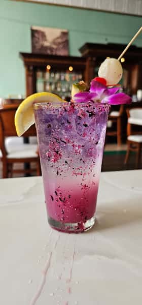 Pink Flamingo a purple and pink breakfast cocktail with a lemon wedge and flower garnish