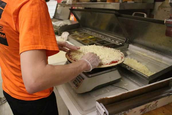 Employee weighing a pizza