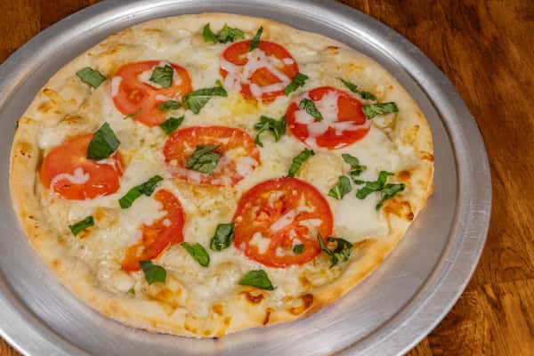 Traditional Margherita pizza with fresh mozzarella, tomato slices, and basil on a golden-baked crust, served on a silver pizza tray.