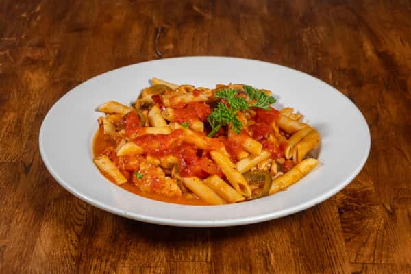 Hearty penne pasta tossed in a chunky tomato sauce with sautéed vegetables and herbs, garnished with fresh parsley on a white plate over a wooden table.