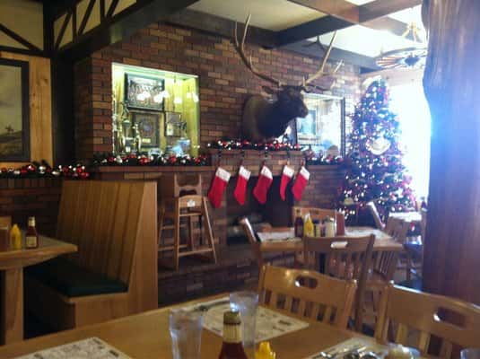 Inside of the restaurant with a christmas tree in the corner and five stockings hanging on the wall,