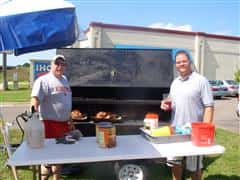 People smiling for a picture in front of a grill