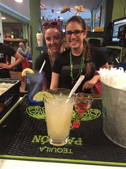 two bartenders posing with a glass of margarita