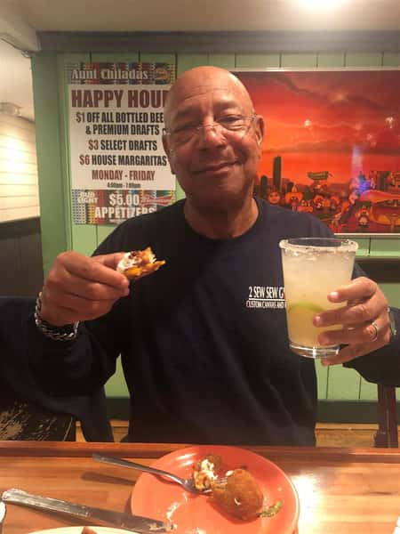 happy customer with a margarita and appetizer in his hand