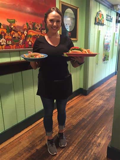 a waitress smiling and holding two plates of food