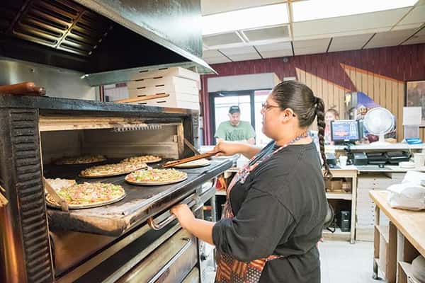 employee putting pizzas in oven