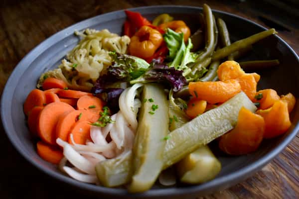 A vibrant antipasto-style plate featuring marinated vegetables, olives, cheeses, and fresh greens. This colorful assortment brings together bold Mediterranean flavors in a fresh and inviting presentation.