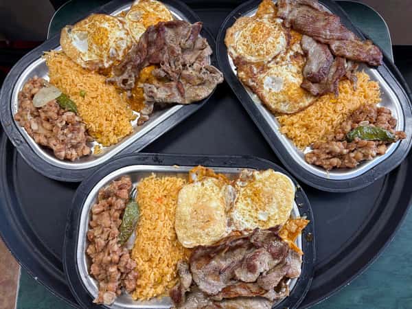 Three metal plates filled with sunny-side-up eggs, grilled meat, Mexican rice, refried beans, and jalapeños on a black tray.