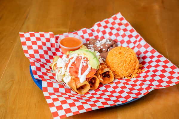 Chicken flautas with white sauce, shredded lettuce, rice, refried beans, and a cup of salsa.