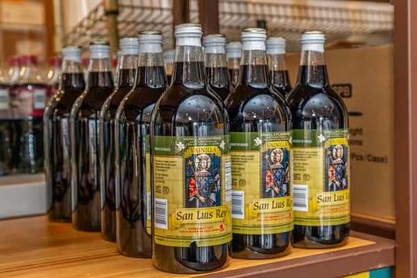 Rows of glass beverage bottles displayed on a wooden counter.