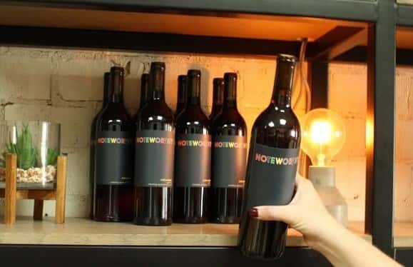 Photo of a hand grabbing a bottle of wine off of a shelf at Town Hall restaurant.