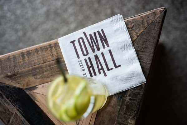 Cocktail and branded cocktail napkin on a wooden side table in Town Hall restaurant.