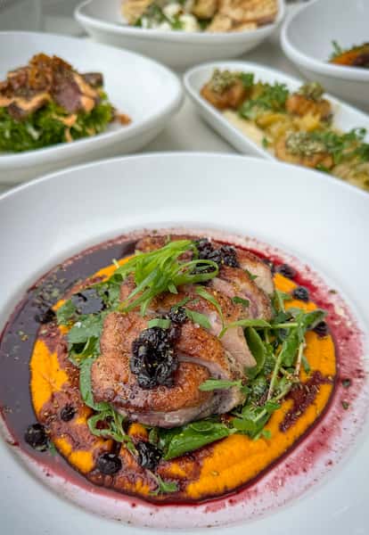 Seared Duck Breast at Town Hall, with carrot puree, cress, truffle vinaigrette + huckleberry gastrique.