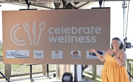 Woman standing in front of a Celebrate Wellness sign
