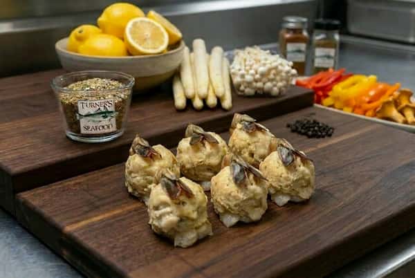 6 baked stuffed shrimp on a display board with lemons, carrots, peppers, and spices