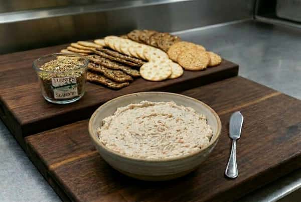 Bowl of smoked salmon spread with flatbread crackers and serving knife