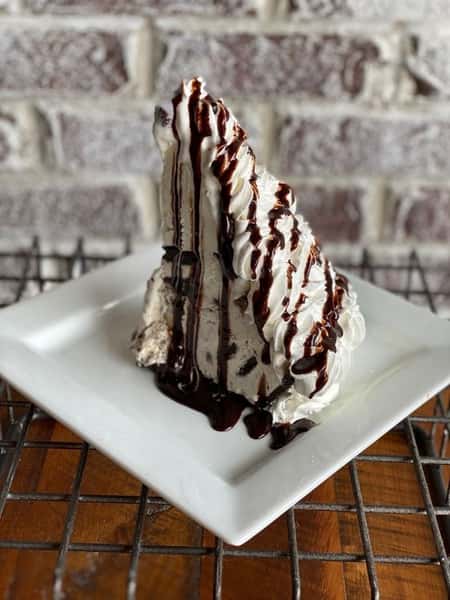 Cookies & cream ice cream and Moose Tracks ice cream atop an Oreo cookie crust and topped with whip cream and drizzled with chocolate syrup.