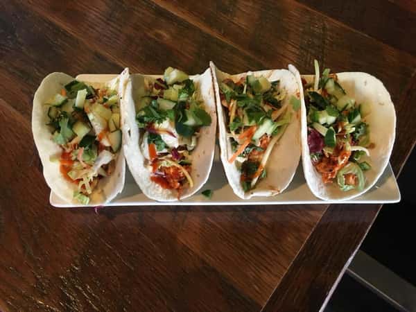 Four tacos lined up on plate