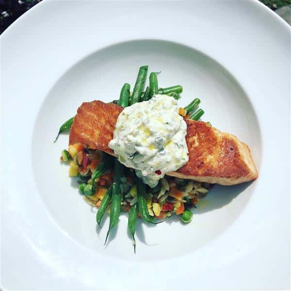 slice of grilled fish on a bed of string beans and mixed veggies