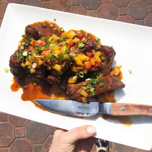 a plate of meat with sauce and mixed veggies