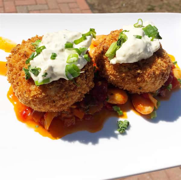 two crab cakes on a bed of veggies