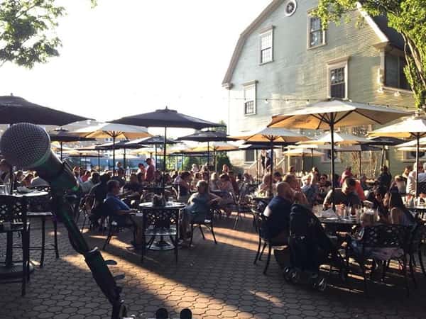 outdoor seating area with many people sitting at round tables under umbrellas