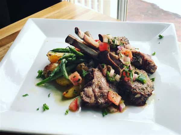 two pieces of meat on the bone with a side of mixed veggies
