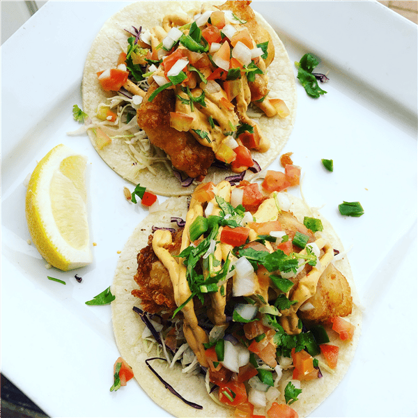 two fish tacos with pico de gallo, cilantro and a wedge lemon