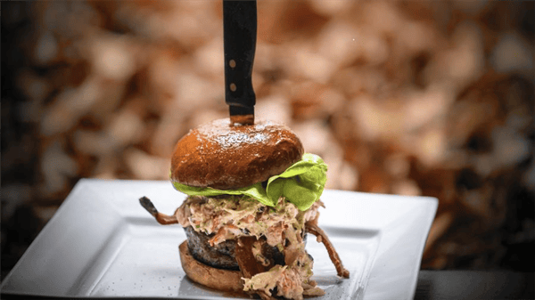a burger with crab meat and lettuce with a knife sticking through it
