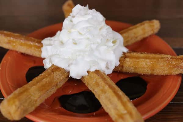 Churros on a plate with whipped cream