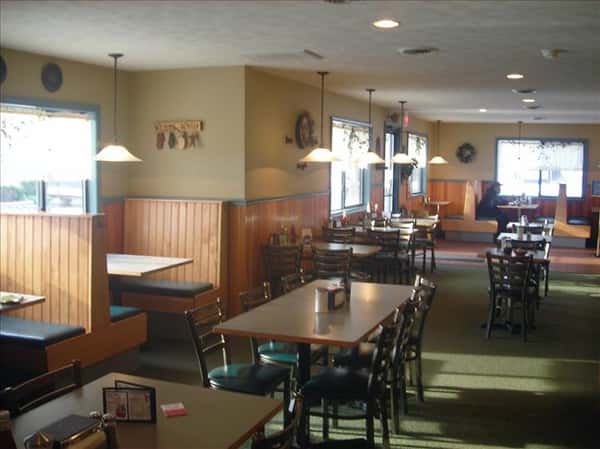 Dining area with chandeliers above and windows in the background
