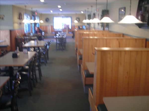 Dining area with chandeliers above and windows in the background