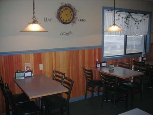 Dining area with chandeliers above and windows in the background