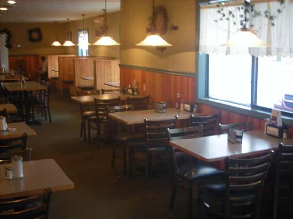 Dining area with chandeliers above and windows in the background