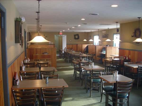 Dining area with chandeliers above and windows in the background