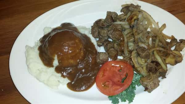 Sausage served with a side of mashed potatoes, lettuce, and tomatoes