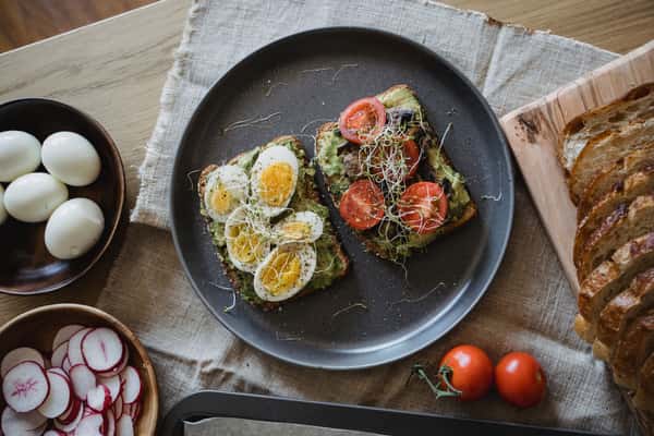 Avocado toast topped with boiled eggs, cherry tomatoes, and mixed vegetables