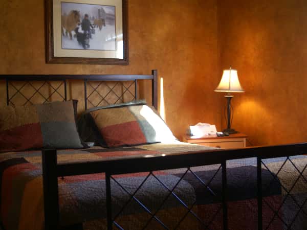 suite with a large bed next to a night stand with a lamp and a decorative picture hanging on the wall