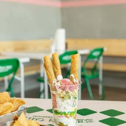 Mexican street corn layered with crema and queso fresco, topped with pink pickled onions and crispy rolled taquitos—fun, modern twist on traditional taqueria snacks.