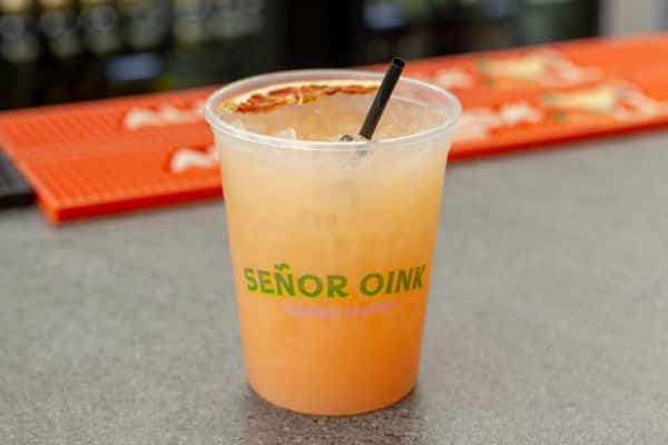 Iced citrus agua fresca served in Señor Oink branded cup with chili rim detail—bright, refreshing Mexican drink.