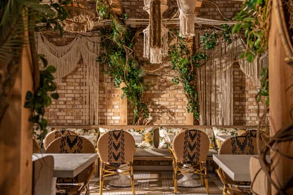Upscale restaurant seating area with tropical greenery, woven textures, and sophisticated modern interior design
