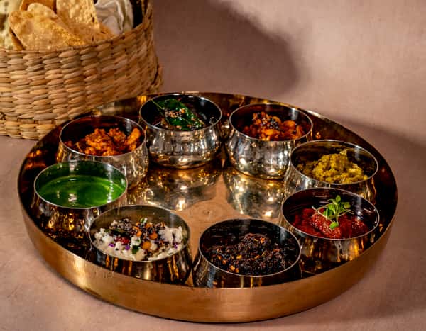 Traditional Indian thali platter with assorted curries, chutneys, and spices served in an upscale dining setting