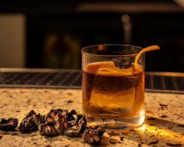 Craft whiskey cocktail served at a stylish upscale bar with warm ambient lighting and modern lounge atmosphere