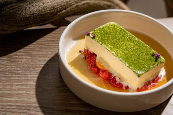 Modern layered dessert with pistachio topping and creamy filling served in an upscale dining setting