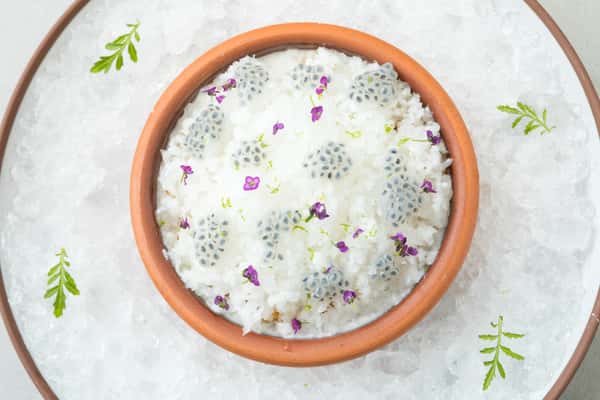 Creamy Indian rice pudding dessert garnished with edible flowers in a minimalist presentation